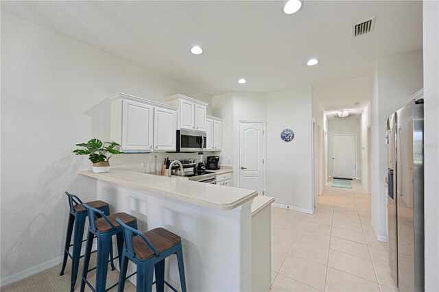 kitchen featuring light tile patterned floors, a breakfast bar, visible vents, light countertops, and appliances with stainless steel finishes