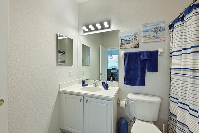 bathroom featuring toilet, a textured wall, and vanity