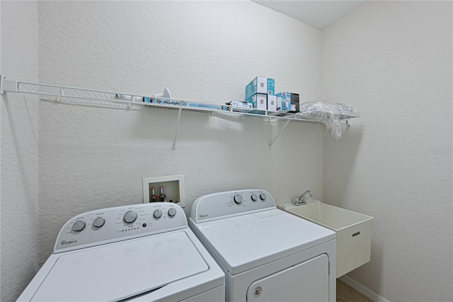 laundry room featuring a textured wall, laundry area, independent washer and dryer, and a sink