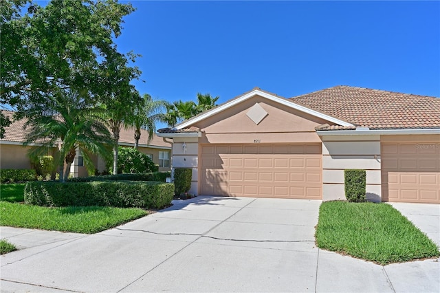 ranch-style house with driveway, an attached garage, a tile roof, and stucco siding