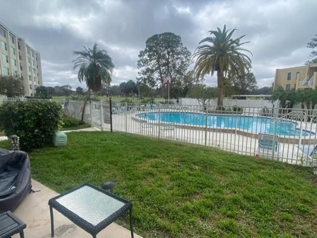 pool with a lawn, a patio, grilling area, and fence