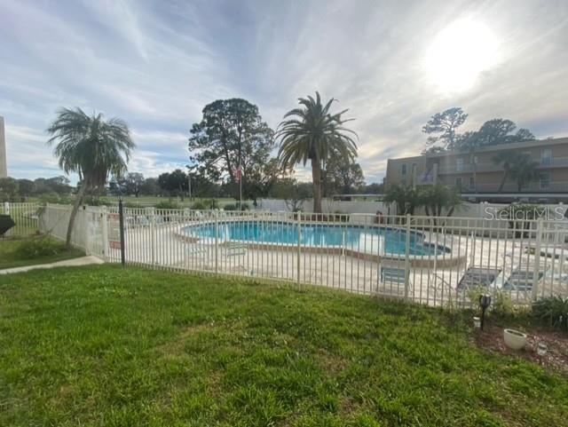 community pool featuring a yard, a patio, and fence