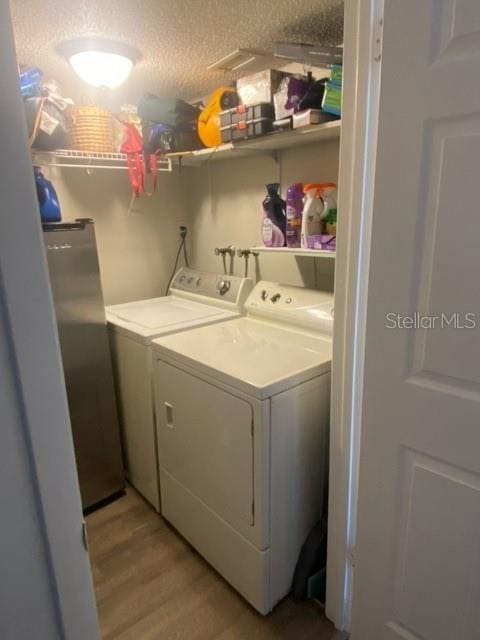 laundry room with a textured ceiling, laundry area, light wood-type flooring, and washing machine and dryer