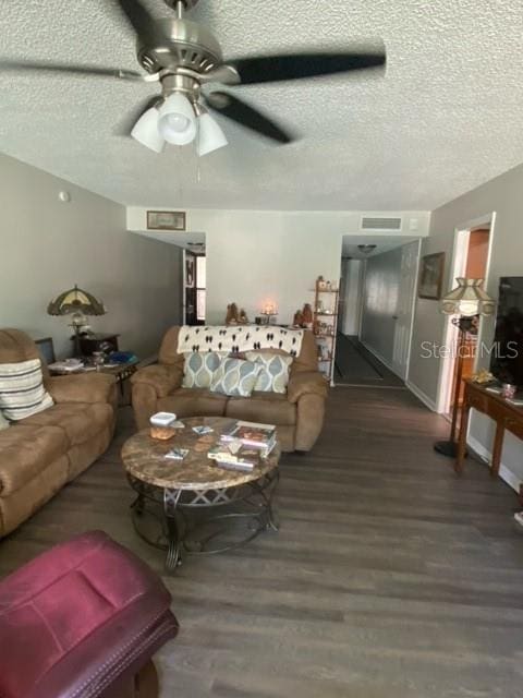 living area with a ceiling fan, visible vents, a textured ceiling, and wood finished floors