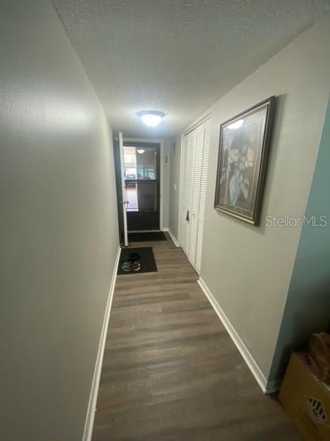 entryway featuring a textured ceiling, wood finished floors, and baseboards