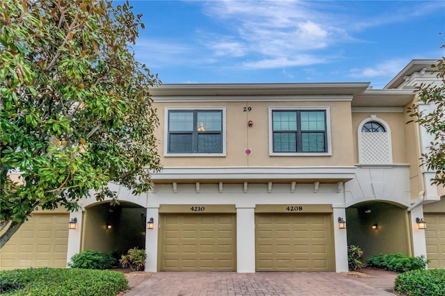 view of front of house with decorative driveway, a garage, and stucco siding