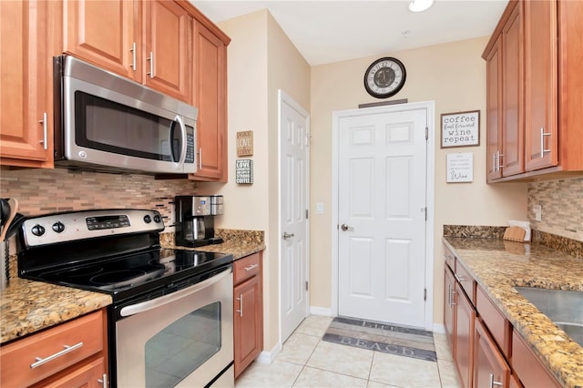 kitchen with light stone counters, appliances with stainless steel finishes, and brown cabinetry