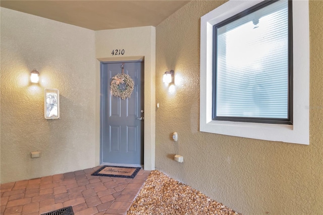 entrance to property featuring visible vents and stucco siding