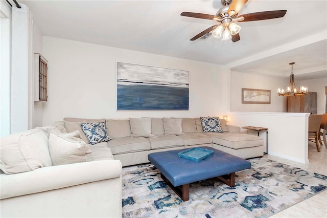 living room with tile patterned floors, ceiling fan with notable chandelier, and baseboards