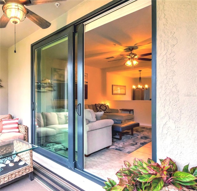 exterior space featuring tile patterned floors, ceiling fan with notable chandelier, and a textured wall