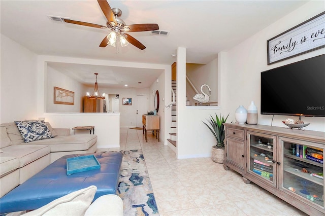 living room with visible vents, ceiling fan with notable chandelier, stairway, and baseboards