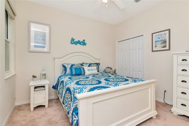 bedroom with a closet, light carpet, baseboards, and ceiling fan