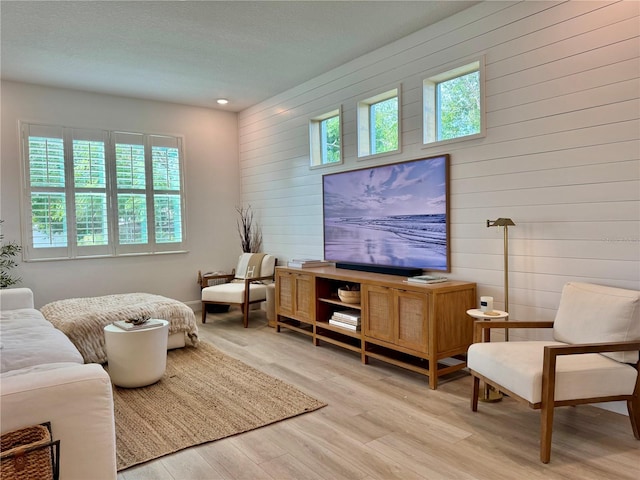 sitting room featuring light wood-style floors, recessed lighting, plenty of natural light, and wood walls