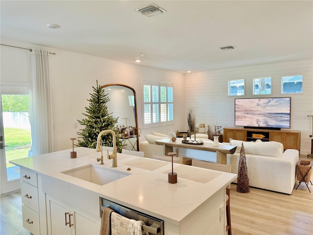 kitchen featuring light wood finished floors, visible vents, open floor plan, and a sink