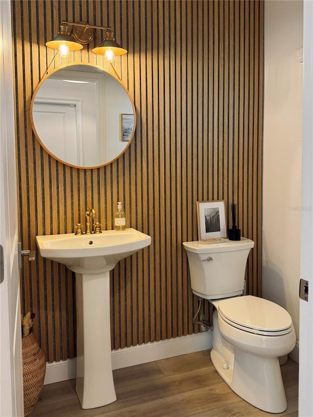 bathroom featuring wallpapered walls, baseboards, and wood finished floors