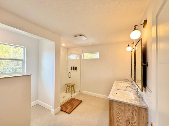 full bathroom featuring double vanity, a stall shower, plenty of natural light, and a sink