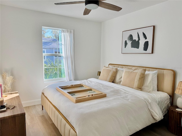 bedroom with a ceiling fan, light wood-type flooring, multiple windows, and baseboards