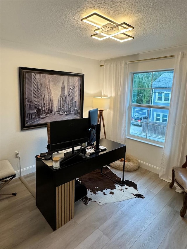 home office featuring a textured ceiling, baseboards, and wood finished floors