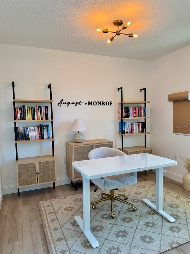 office with a textured ceiling, baseboards, and wood finished floors