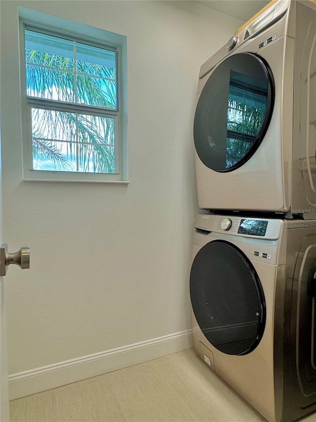 laundry room featuring laundry area, baseboards, and stacked washer / dryer