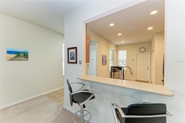 kitchen featuring a kitchen bar, recessed lighting, carpet, and baseboards