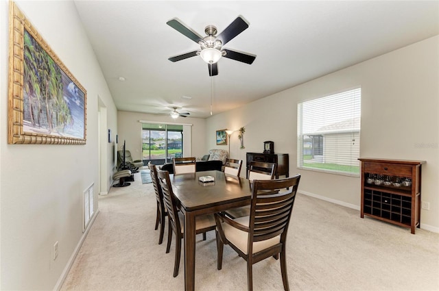 dining space featuring baseboards, visible vents, and light colored carpet