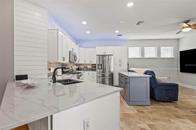 kitchen featuring stainless steel appliances, visible vents, white cabinets, light stone countertops, and a peninsula