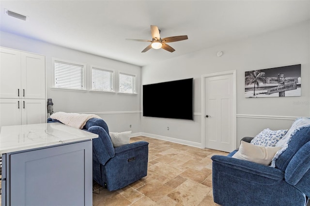 living area with baseboards, visible vents, a ceiling fan, and stone finish flooring