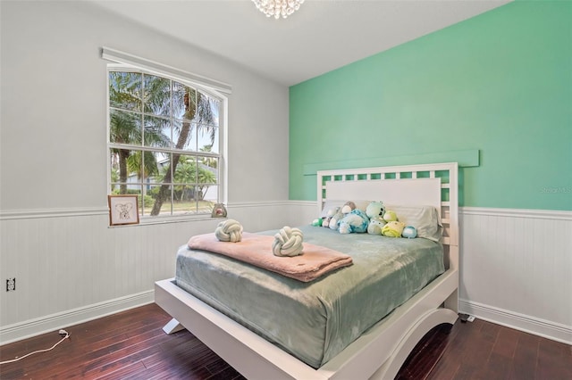 bedroom with hardwood / wood-style floors and wainscoting