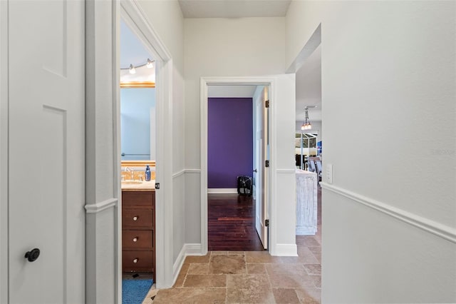 hallway featuring stone tile flooring and baseboards