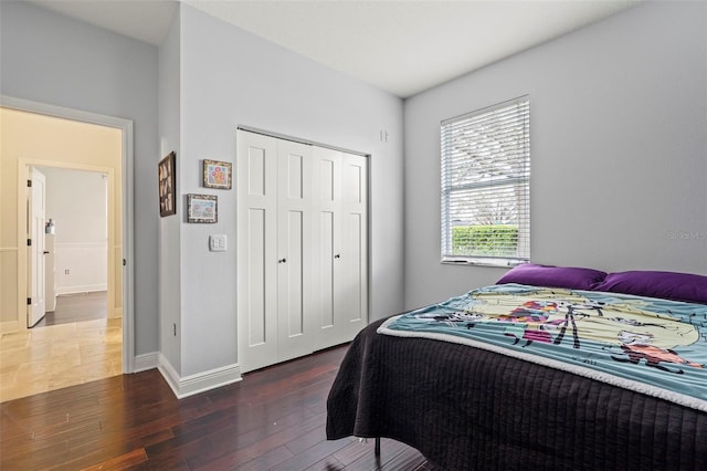 bedroom featuring a closet, wood-type flooring, and baseboards