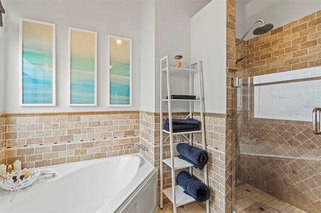 full bathroom with a wainscoted wall, a stall shower, a bath, and tile walls