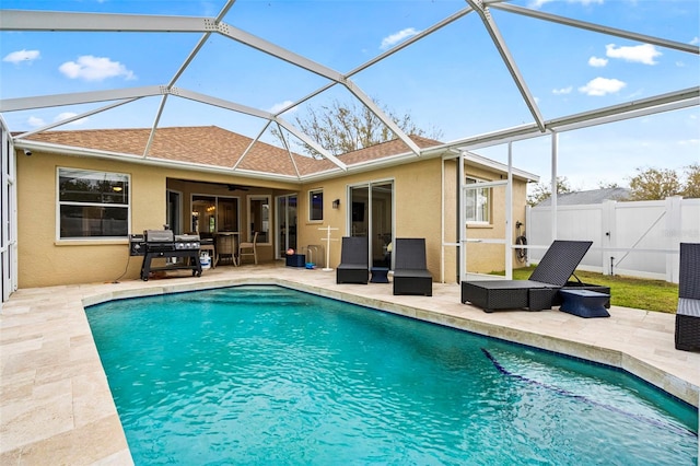 view of pool featuring glass enclosure, fence, a fenced in pool, and a patio