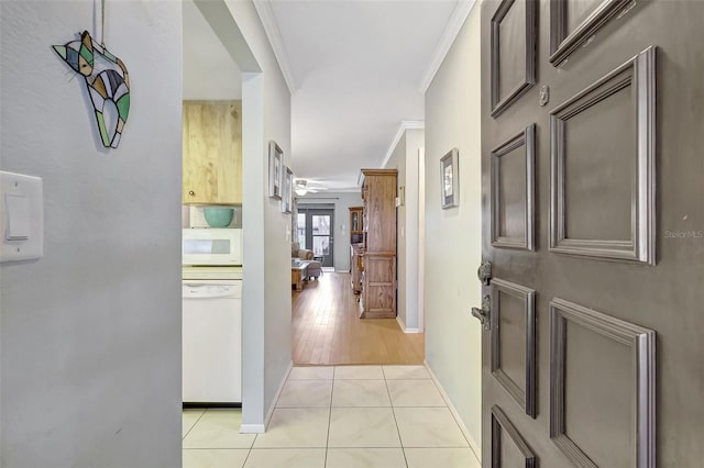 hallway featuring ornamental molding, light tile patterned flooring, and baseboards