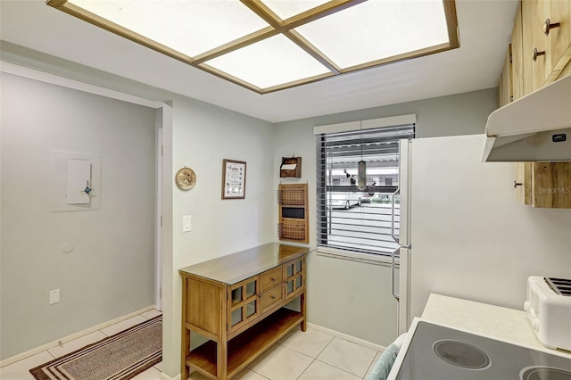 kitchen with light tile patterned floors, under cabinet range hood, a baseboard heating unit, light countertops, and freestanding refrigerator