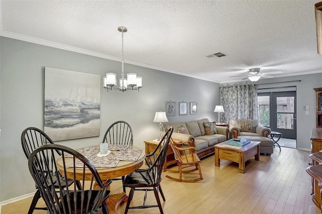 dining room with a textured ceiling, visible vents, baseboards, ornamental molding, and light wood-type flooring