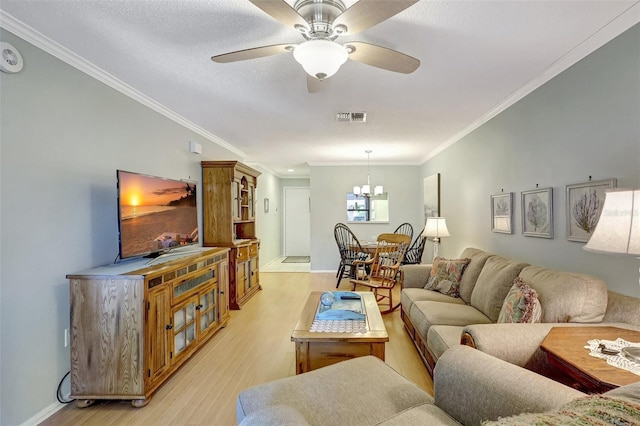 living room with crown molding, ceiling fan with notable chandelier, visible vents, and light wood-style floors