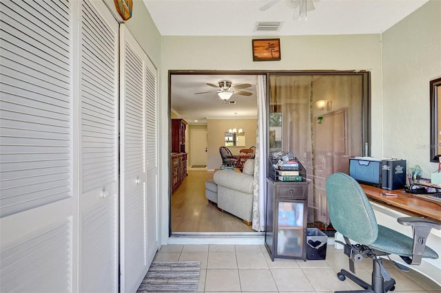 office area with light tile patterned floors, visible vents, and ceiling fan with notable chandelier