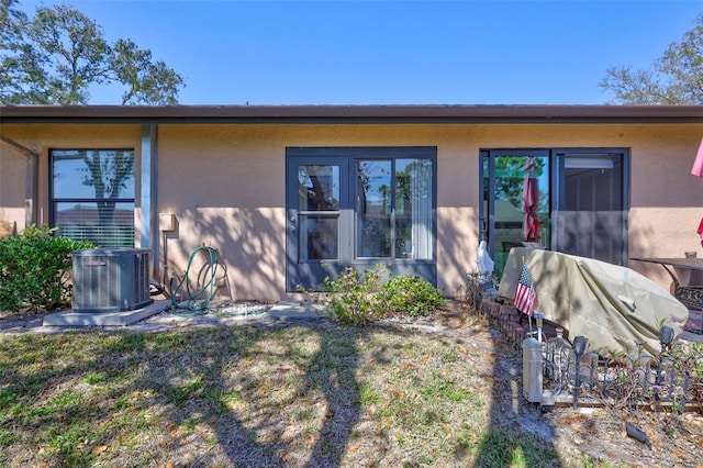 rear view of property with central AC unit and stucco siding