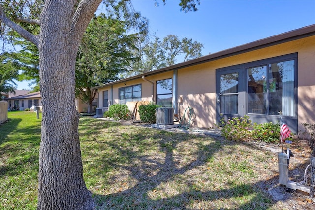 view of front of house featuring a front lawn, stucco siding, and central air condition unit