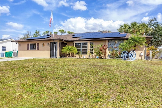 single story home featuring a front yard, solar panels, fence, and stucco siding