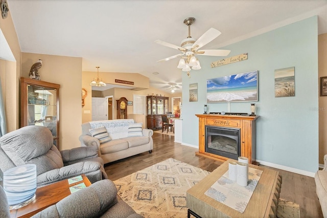 living area with baseboards, a ceiling fan, a glass covered fireplace, lofted ceiling, and wood finished floors