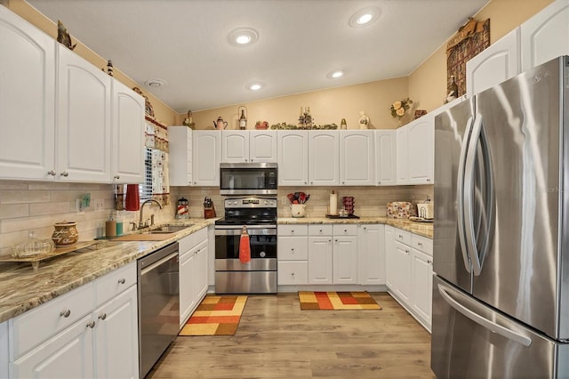 kitchen featuring tasteful backsplash, appliances with stainless steel finishes, white cabinets, and a sink