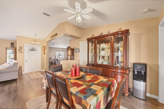 dining room featuring a ceiling fan, visible vents, vaulted ceiling, and wood finished floors