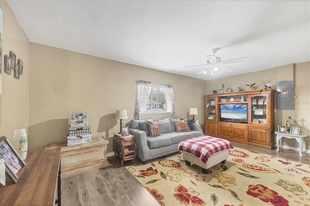 living room with ceiling fan, baseboards, and wood finished floors