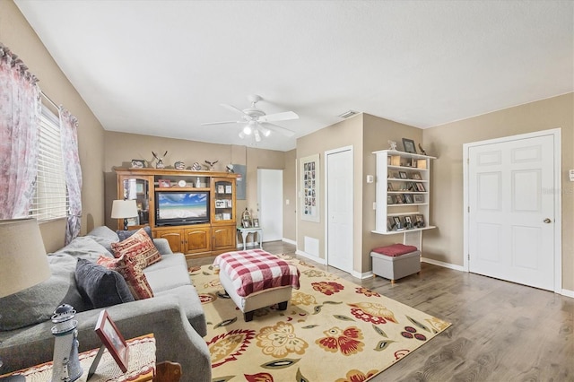 living area with a ceiling fan, visible vents, baseboards, and wood finished floors