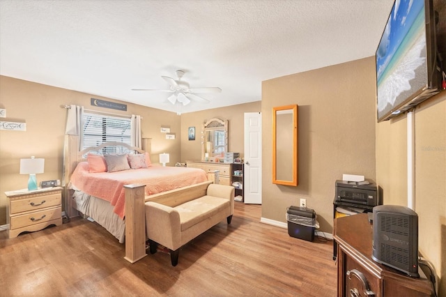 bedroom with a textured ceiling, ceiling fan, light wood-type flooring, and baseboards