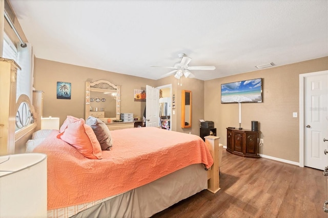 bedroom with a ceiling fan, visible vents, baseboards, and wood finished floors