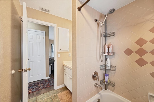 bathroom with washtub / shower combination, visible vents, and vanity