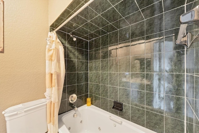 bathroom with a textured wall, a combined bath / shower with jetted tub, and toilet